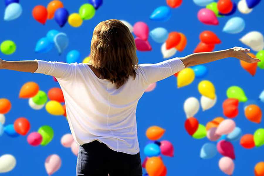 Lady happy with colourful balloons in the sky